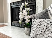 Thumbnail 13 of 26 - a vase with white flowers in front of a fireplace