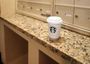 Thumbnail 41 of 43 - A Starbucks cup sits on a granite countertop in front of a wall of lockers.