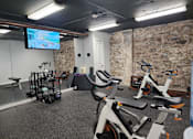 Thumbnail 37 of 43 - A gym with exercise bikes and a television screen.