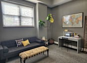 Thumbnail 5 of 43 - A living room with a sofa, a chair, a table, and a plant.