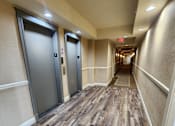 Thumbnail 33 of 43 - A long hallway with wood floors and two elevators.