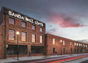Thumbnail 6 of 9 - A red brick building with the words "SANDA MILL LOFTS" on the top.