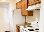 Thumbnail 8 of 12 - A white refrigerator and oven in a kitchen with wooden cabinets.