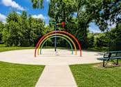 Thumbnail 5 of 5 - A playground with a rainbow-colored arch and a bench.