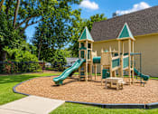 Thumbnail 4 of 5 - A playground with a green slide and wooden structure.
