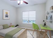 Thumbnail 13 of 23 - A bedroom with a bed, desk, and chair.