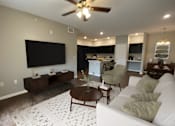 Thumbnail 11 of 23 - A living room with a white couch, a coffee table, and a flat screen TV mounted on the wall.