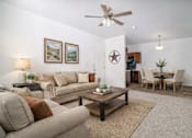 Thumbnail 7 of 25 - A living room with a beige couch, a coffee table, and a ceiling fan.