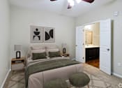 Thumbnail 12 of 23 - A bedroom with a bed, two lamps, and two framed pictures on the wall.