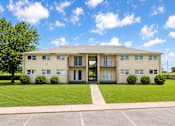 Thumbnail 9 of 10 - A large building with a parking lot in front.