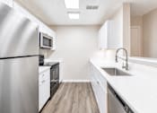 Thumbnail 40 of 43 - A kitchen with white cabinets and a stainless steel refrigerator.