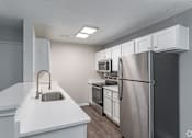Thumbnail 13 of 35 - A kitchen with white countertops and stainless steel appliances.