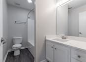 Thumbnail 17 of 35 - A white toilet in a small bathroom with a white sink and a mirror.