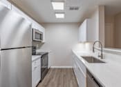 Thumbnail 14 of 35 - A modern kitchen with white appliances and cabinets.
