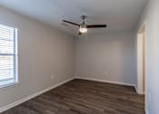 Thumbnail 11 of 35 - A room with a ceiling fan and wooden flooring.