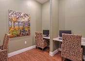 Thumbnail 6 of 23 - A painting of a tree with autumn leaves hangs on a wall above a desk with two chairs.