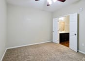 Thumbnail 21 of 23 - A room with a carpeted floor and a ceiling fan.