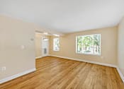 Thumbnail 12 of 21 - A room with wooden flooring and a window showing trees outside.