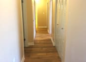 Thumbnail 4 of 21 - A long hallway with white walls and wood floors.