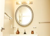 Thumbnail 8 of 21 - A bathroom with a round mirror and a light above it.