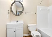 Thumbnail 18 of 21 - A white toilet sits next to a white sink in a small bathroom.
