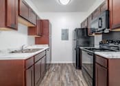 Thumbnail 8 of 25 - A kitchen with dark wood cabinets and black appliances.