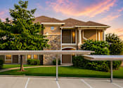 Thumbnail 44 of 61 - A house with a stone wall and a covered parking area.