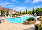 Thumbnail 57 of 61 - A large outdoor swimming pool surrounded by patio furniture and trees.