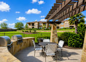 Thumbnail 52 of 61 - A patio with a table and chairs under a wooden pergola.