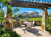 Thumbnail 58 of 61 - A patio with a table and chairs under a wooden pergola.