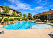 Thumbnail 53 of 61 - A large outdoor swimming pool surrounded by lounge chairs and palm trees.