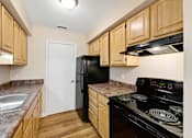 Thumbnail 1 of 21 - A kitchen with wooden cabinets and a black stove top oven.