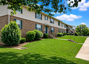 Thumbnail 3 of 4 - Apartment building with green bushes in front.