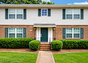Thumbnail 2 of 4 - A house with a green door and two windows with green shutters.