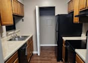 Thumbnail 35 of 38 - A kitchen with wooden cabinets and a black fridge.