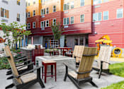 Thumbnail 12 of 22 - A patio with chairs and a table in front of a building.