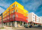 Thumbnail 8 of 22 - A multi-story building with a yellow, red, and white exterior.