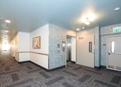 Thumbnail 17 of 22 - A hallway with a carpeted floor and a white wall with a picture on it.