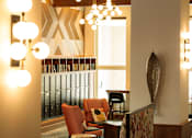 Thumbnail 20 of 22 - A room with a chair and a table with a lamp on it.