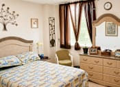 Thumbnail 2 of 8 - A bedroom with a bed, chair, and a clock on the wall.