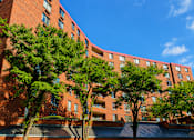 Thumbnail 1 of 8 - A red brick building with trees in front.