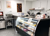 Thumbnail 7 of 8 - A display case filled with pastries sits in the middle of a clean, white-walled bakery.