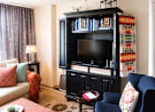 Thumbnail 4 of 8 - A living room with a black entertainment center and a blue chair.