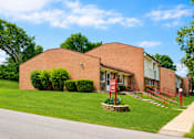 Thumbnail 5 of 7 - A red brick building with a red gate in front.