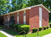 Thumbnail 3 of 4 - A red brick house with a white door and windows.