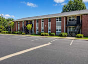 Thumbnail 4 of 4 - A parking lot in front of a brick building with a black staircase.