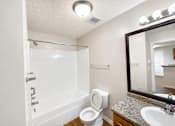 Thumbnail 6 of 12 - A white bathroom with a toilet, sink, and bathtub.