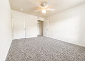 Thumbnail 3 of 12 - A room with a ceiling fan and carpeted floor.