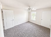 Thumbnail 8 of 12 - A room with a ceiling fan and carpeted floor.