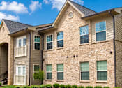 Thumbnail 1 of 12 - A large, multi-story residential building with a stone facade and multiple windows.